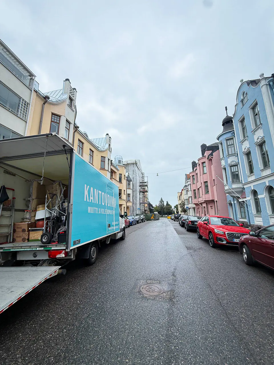 Kantovoiman muuttoauto takaovet auki kerrostalokadulla Helsingin kantakaupungissa