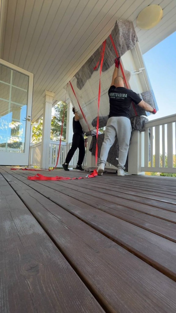 Kantovoiman muuttajat nostavat patjaa terassilla kantoremmien avulla