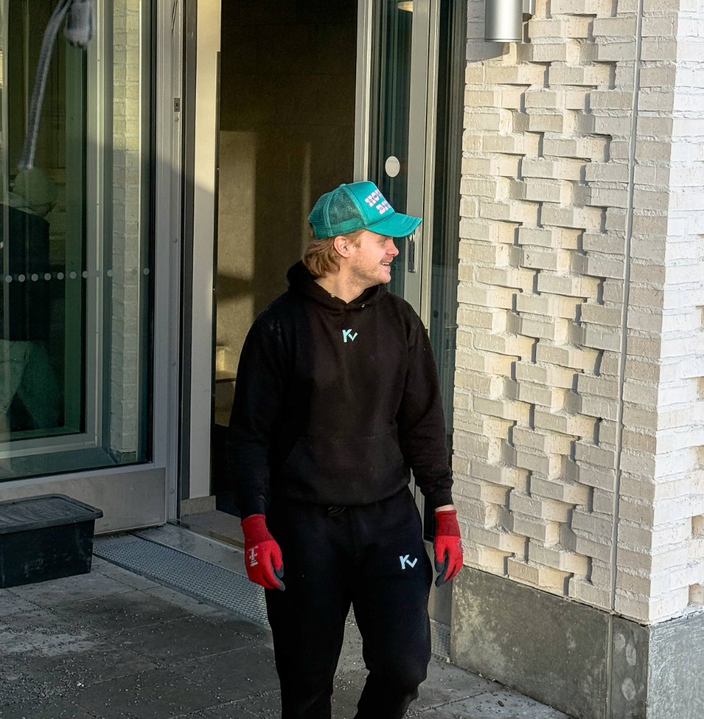 Kantovoiman työntekijä hymyilee kerrostalon ovella työasussa