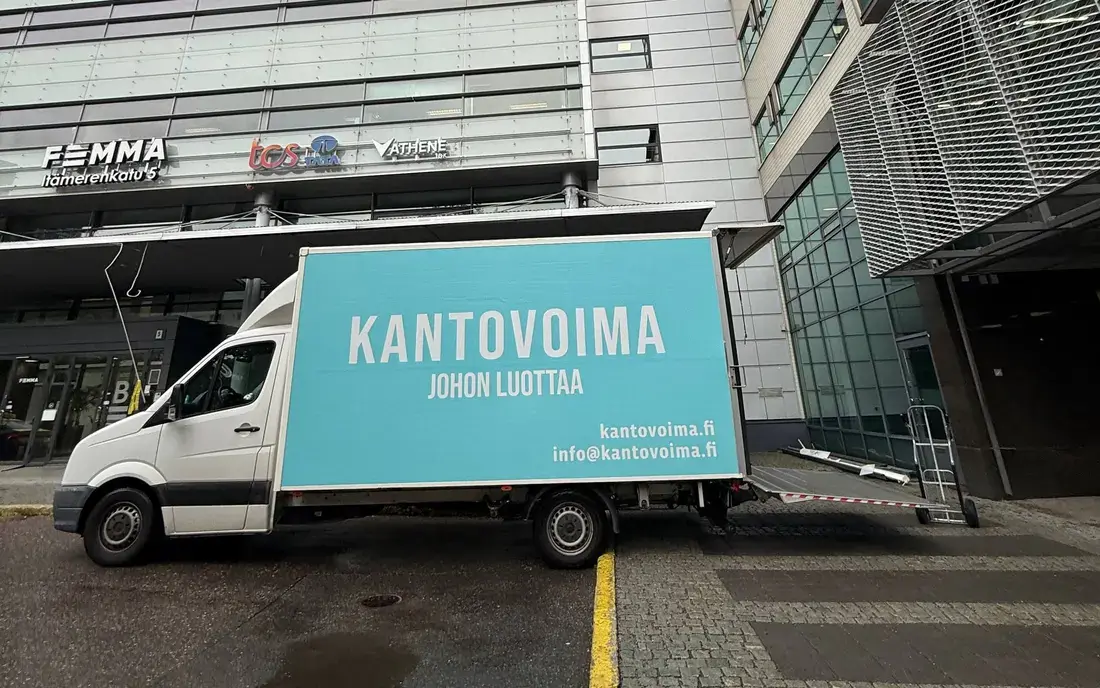 Kantovoima's turquoise moving truck parked in front of an office building
