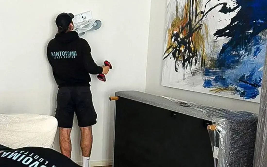 Kantovoima movers wrapping furniture in protective film in a living room